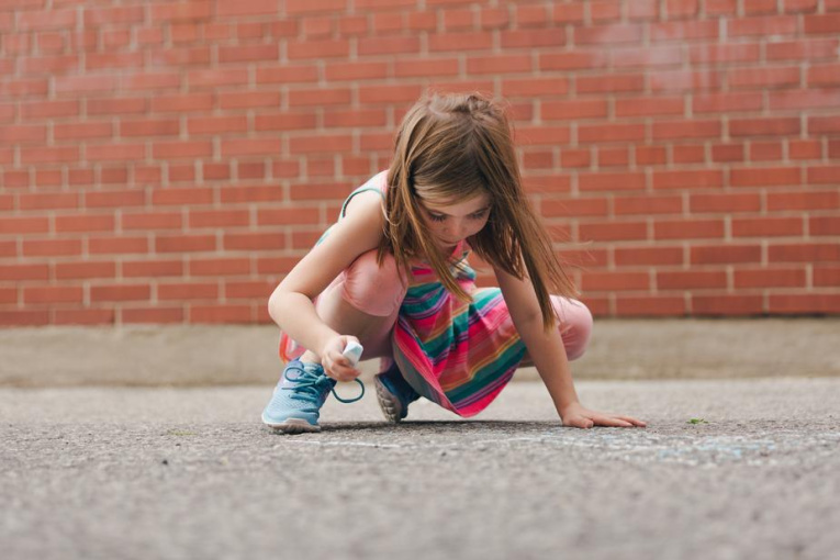girl-using-sidewalk-chalk-in-schoolyard