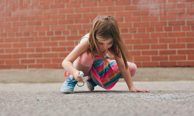 girl-using-sidewalk-chalk-in-schoolyard
