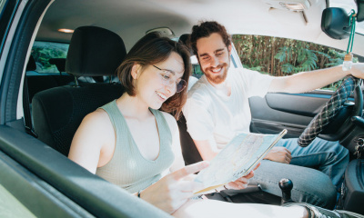 two-people-in-a-car-look-at-a-map-while-smiling
