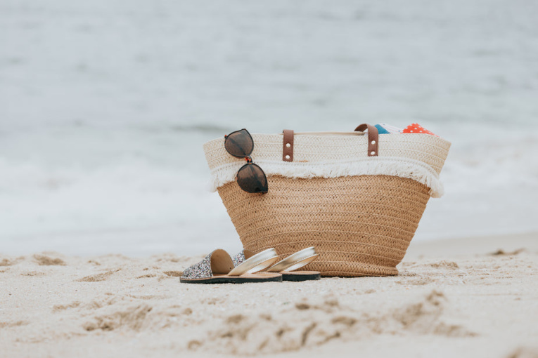 sandals-and-a-beach-bag-on-a-white-sandy-beach