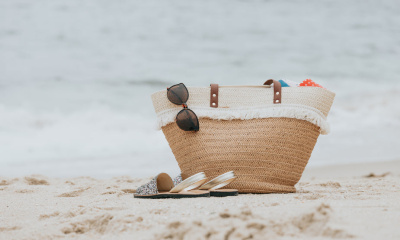 sandals-and-a-beach-bag-on-a-white-sandy-beach