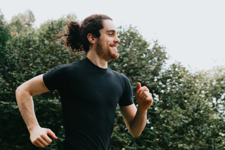 a-person-in-black-smiling-as-they-run-outdoors