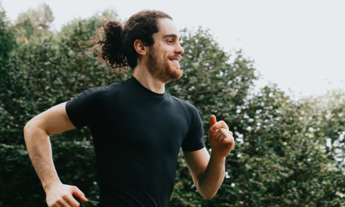 a-person-in-black-smiling-as-they-run-outdoors