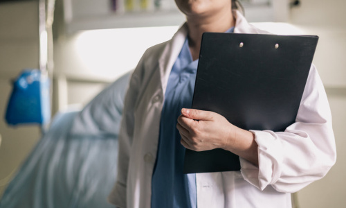 female-medical-professional-holds-clipboard-in-hospital-room