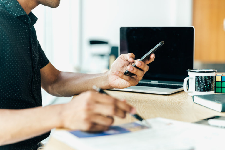 man-at-desk-looking-at-his-mobile