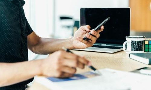 burst-matthew-henry-man-at-desk-looking-at-his-mobile